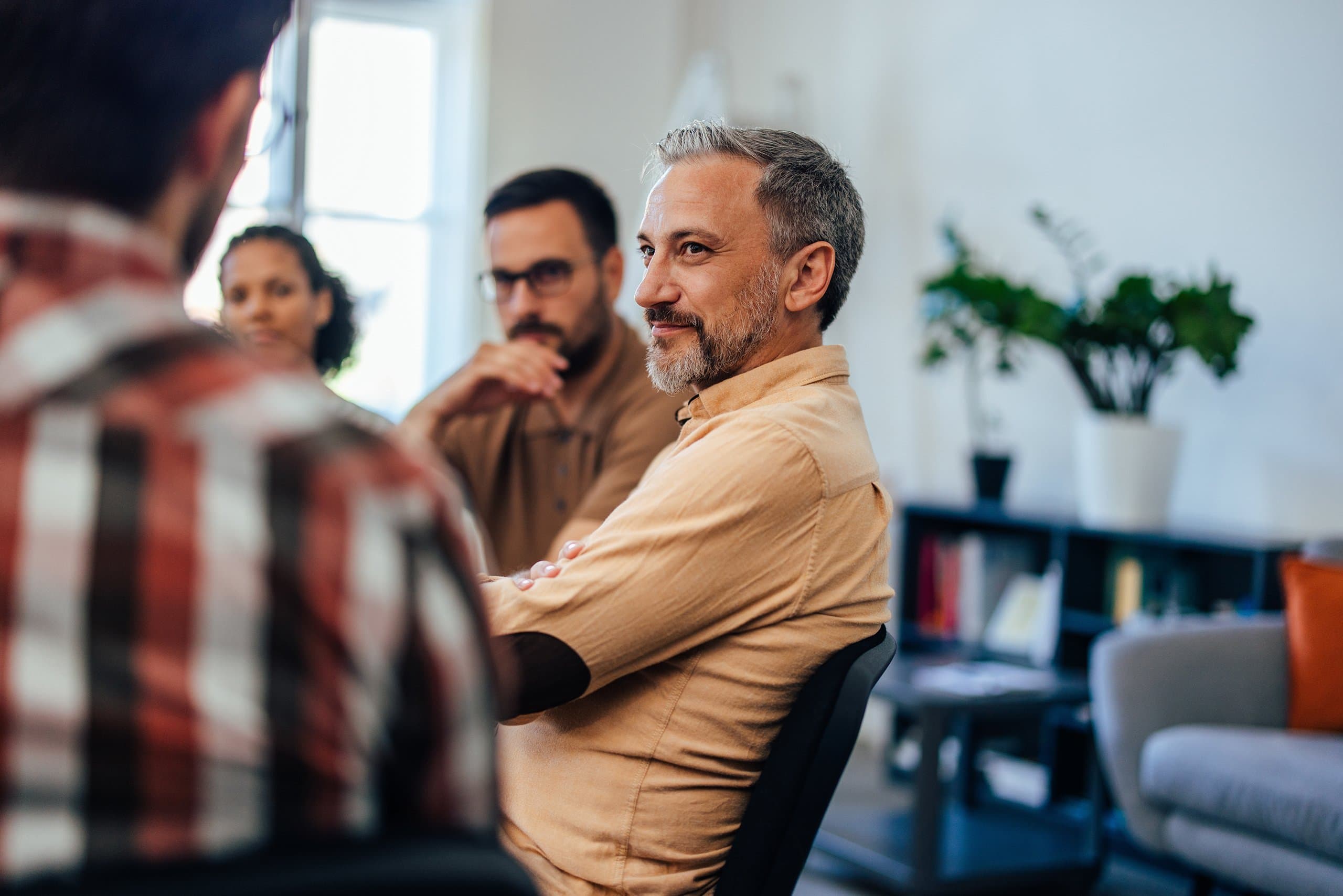 man smiles listens in support group