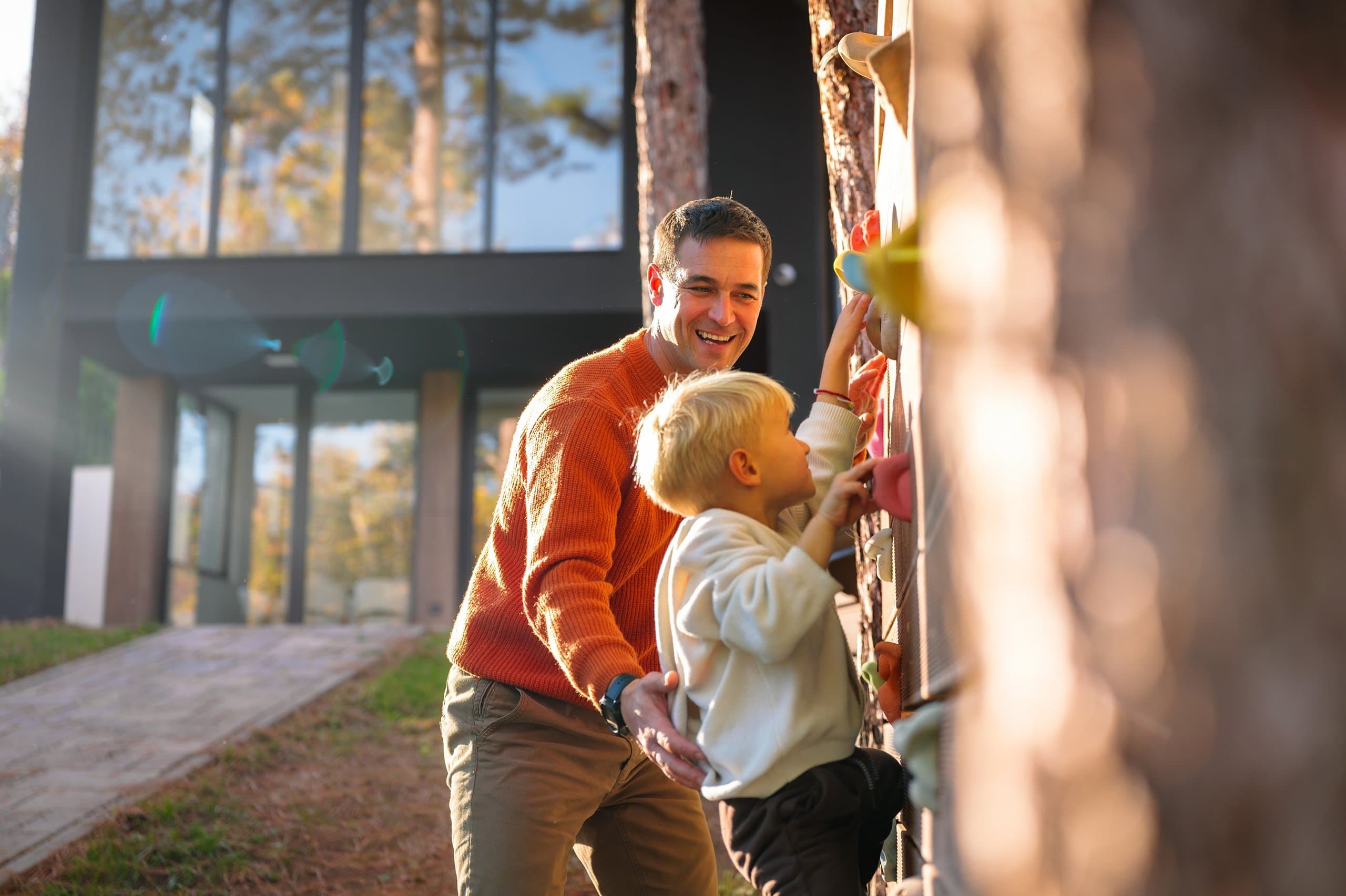 father helps son on climbing wall