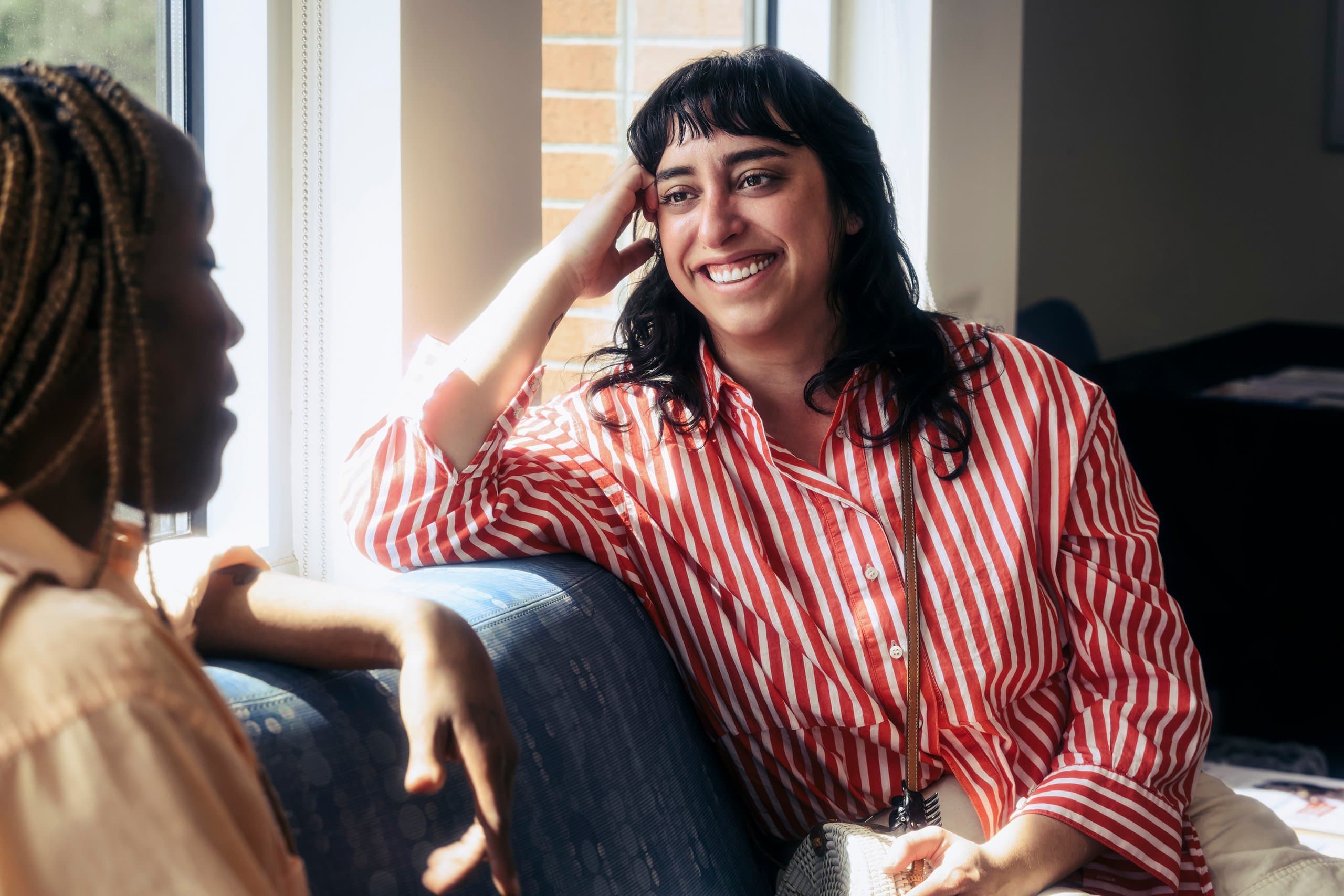 smiling woman smiles on couch talking to another