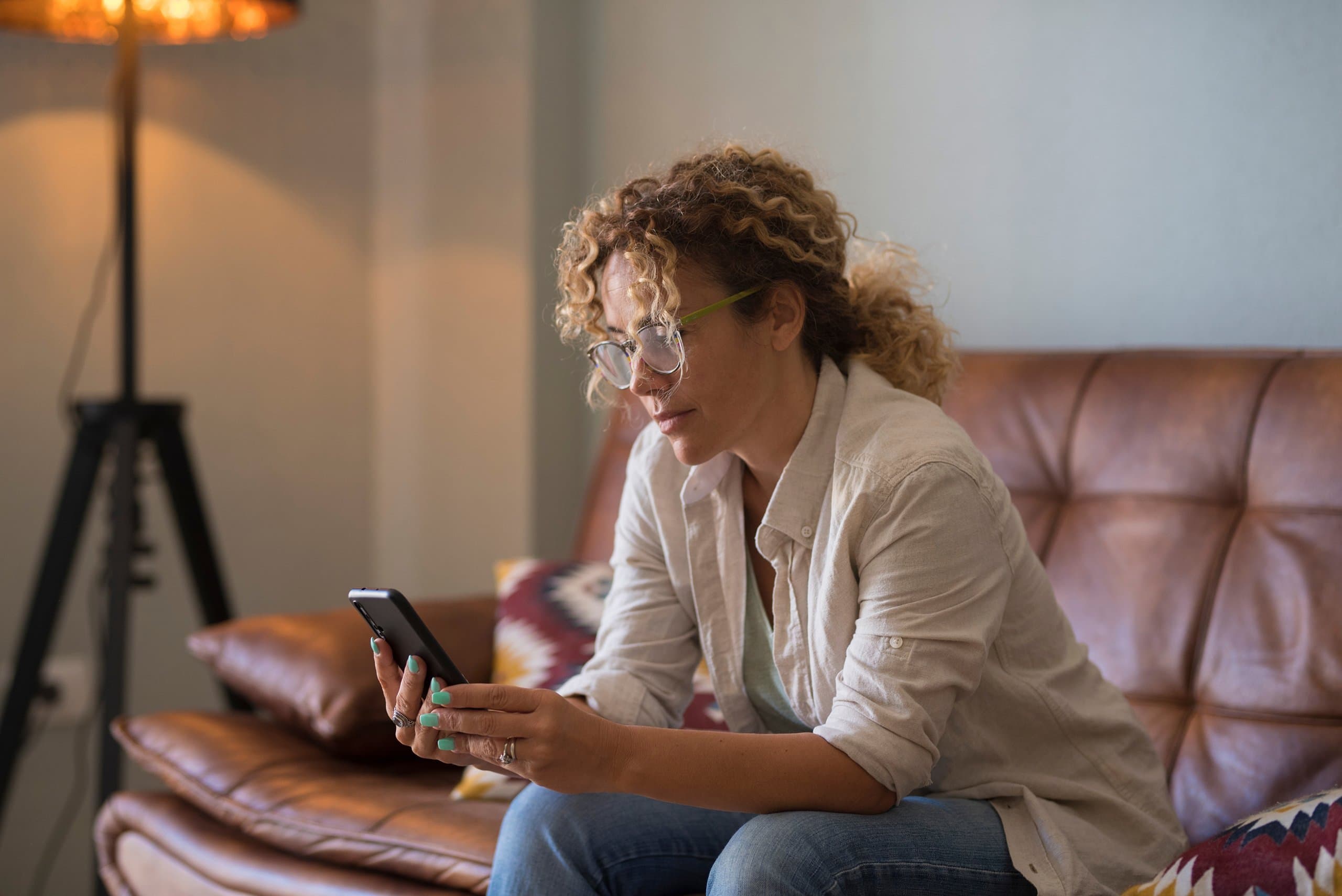 solemn woman on couch looking at phone