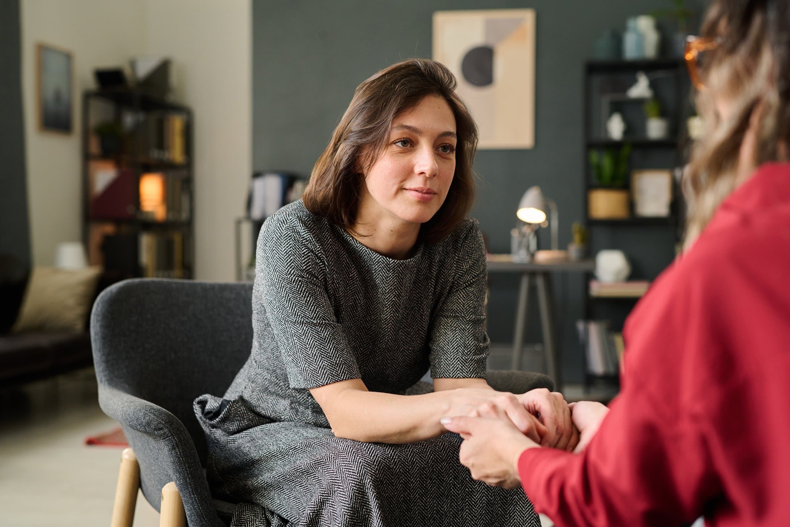woman sitting and holding hands with another