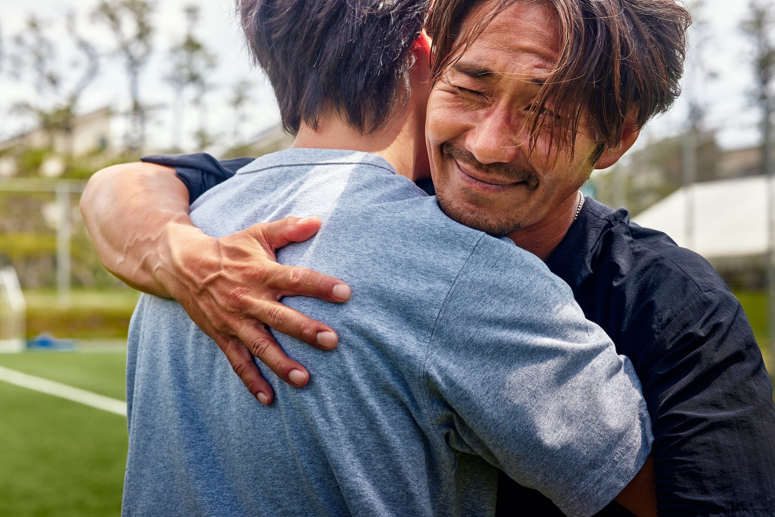 man hugs another relieved tears
