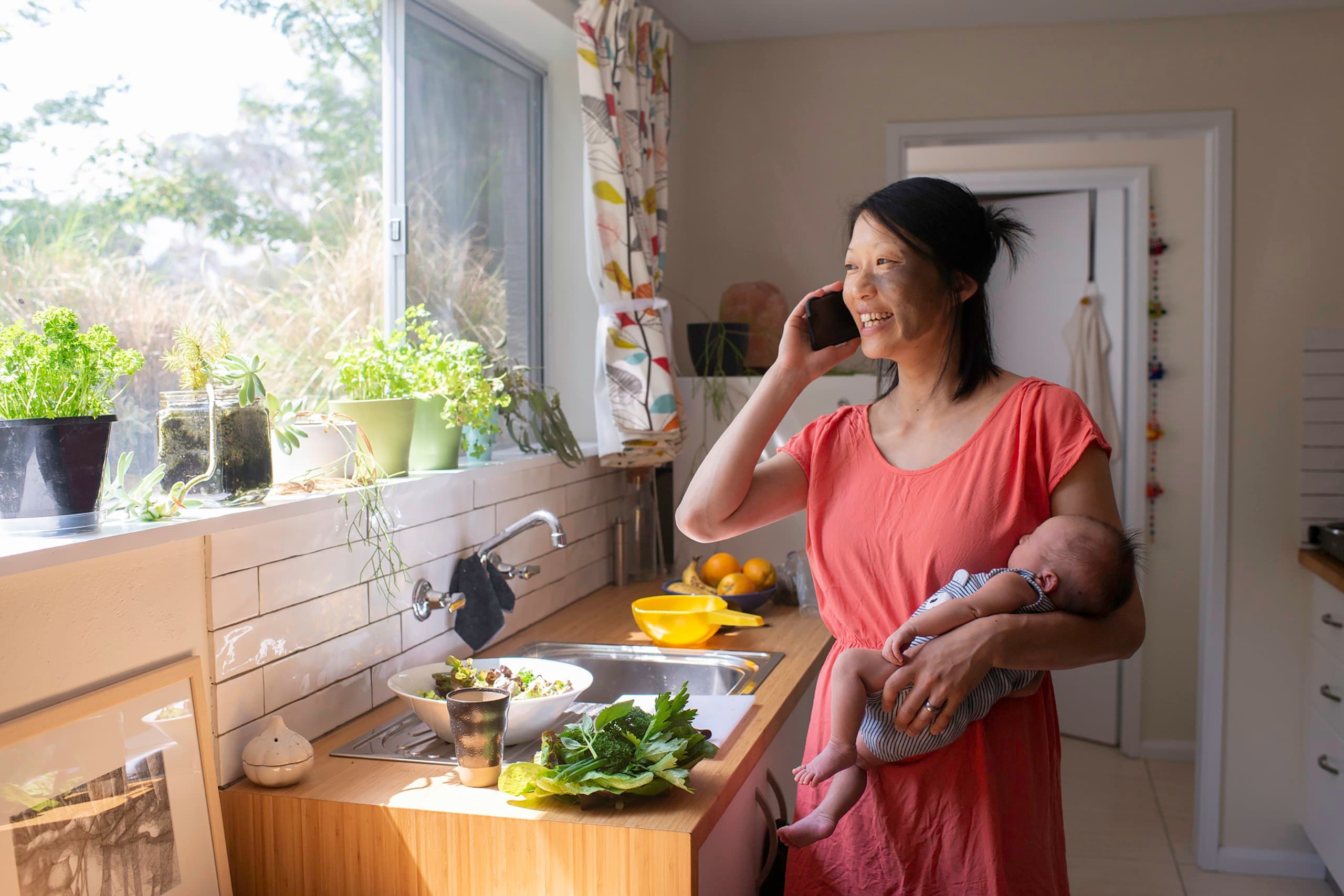 mother at home on phone holding baby